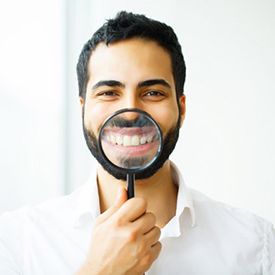 man showing off his pearly whites with a magnifying glass