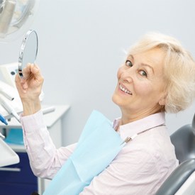 An older woman smiling while sitting in the dentist chair