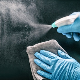 person spraying sanitizer and wiping down a surface with a cloth